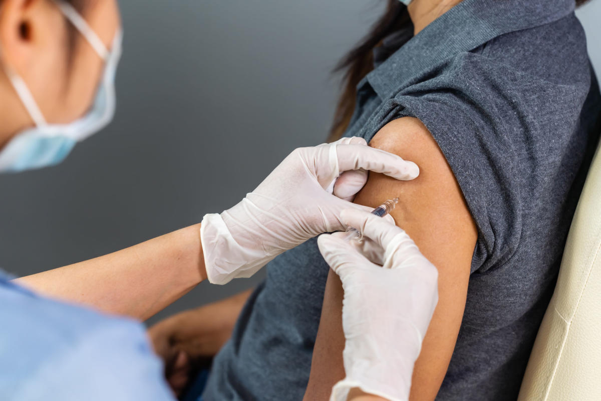 doctor in gloves holding syringe and making injection to patient