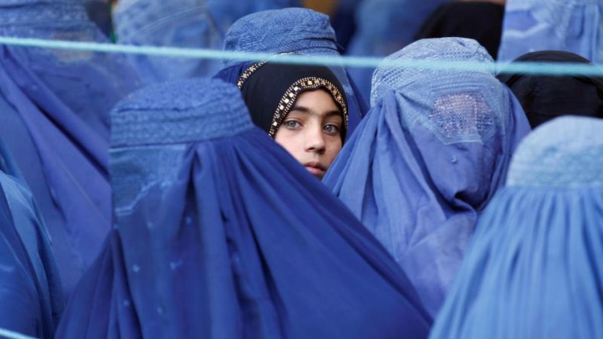 A girl looks on among Afghan women lining up to receive relief assistance, during the holy month of Ramadan in Jalalabad